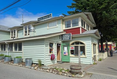 Skagway, AK, ABD - 25 Haziran 2024: Bir içki dükkanı ve tarihi bir han Skagway 'in turistik bölgesinde eski bir cadde köşesinde yer alıyor.