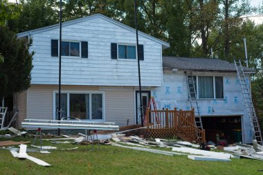 Twinsburg, OH, USA - 2 Ekim 2024: Bir ev yenileme projesinin üç aşaması: Sol üstte eski alüminyum kaplama, sol altta yeni vinil kaplama ve sağda yeni yalıtım panelleri.