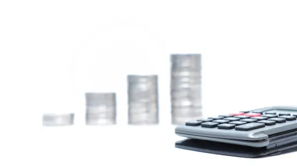 Beyaz arka planda hesap makinesi, iş büyüme konsepti ve mali büyüme içeren madeni para yığınlarının artması