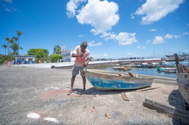 Salvador, Bahia - Brezilya - 30 Eylül 2024: Güneşli bir günde teknesini tamir eden balıkçı.