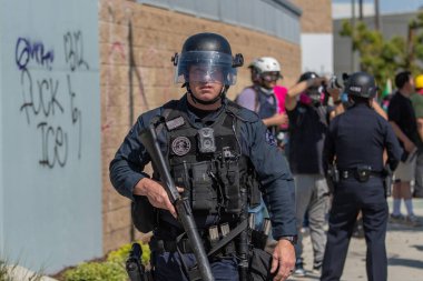 Los Angeles, ABD 8 Haziran 2025 LAPD memuru şehir merkezindeki göçmen haklarına destek ve genişletilmiş ICE operasyonlarına karşı gözcülük yapıyor..