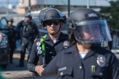 Los Angeles, ABD 8 Haziran 2025 LAPD memuru şehir merkezindeki göçmen haklarına destek ve genişletilmiş ICE operasyonlarına karşı gözcülük yapıyor..