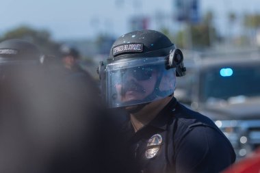 Los Angeles, ABD 8 Haziran 2025 LAPD memuru şehir merkezindeki göçmen haklarına destek ve genişletilmiş ICE operasyonlarına karşı gözcülük yapıyor..