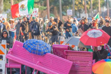 Los Angeles, ABD, 8 Haziran 2025. İCE operasyonlarının genişletilmesi ve göçmen haklarına destek gösterileri sırasında park banklarıyla kurulan geçici barikatların arkasına sığınan protestocular,