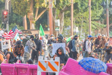 Los Angeles, ABD, 8 Haziran 2025. İCE operasyonlarının genişletilmesi ve göçmen haklarına destek gösterileri sırasında park banklarıyla kurulan geçici barikatların arkasına sığınan protestocular,