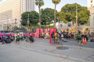 Los Angeles, ABD, 8 Haziran 2025. İCE operasyonlarının genişletilmesi ve göçmen haklarına destek gösterileri sırasında park banklarıyla kurulan geçici barikatların arkasına sığınan protestocular,