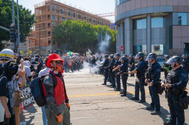 Los Angeles, ABD, 8 Haziran 2025: Los Angeles polis memurları, genişletilmiş ICE operasyonlarına ve göçmen haklarına karşı düzenlenen bir gösteride protestocularla karşı karşıya