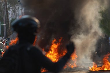 Los Angeles, ABD, 8 Haziran 2025: Göçmen haklarının desteklenmesi ve genişletilmiş ICE operasyonlarına karşı düzenlenen bir gösteri sırasında yanan arabanın üzerinde duran protestocu