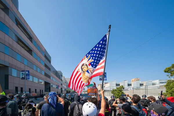 Los Angeles, ABD, 8 Haziran 2025: Protestocu, göçmen haklarının desteklenmesi ve genişletilmiş ICE operasyonlarına karşı düzenlenen bir gösteride Amerikan bayrağını kaldırdı