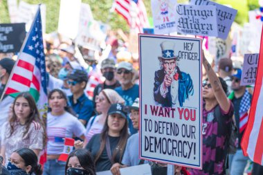 Los Angeles, Kaliforniya, ABD, 14 Temmuz 2025, Hükümetin politikalarını protesto eden ve demokrasi ve göçmen haklarını destekleyen protestocular ellerinde sloganlar tutuyorlar..