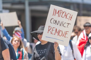 Los Angeles, Kaliforniya, ABD, 14 Temmuz 2025, Hükümetin politikalarını protesto eden ve demokrasi ve göçmen haklarını destekleyen protestocular ellerinde sloganlar tutuyorlar..