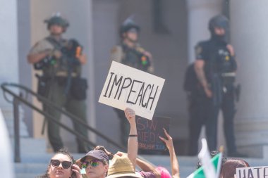 Los Angeles, Kaliforniya, ABD, 14 Temmuz 2025, Hükümetin politikalarını protesto eden ve demokrasi ve göçmen haklarını destekleyen protestocular ellerinde sloganlar tutuyorlar..