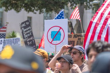 Los Angeles, Kaliforniya, ABD, 14 Temmuz 2025, Hükümetin politikalarını protesto eden ve demokrasi ve göçmen haklarını destekleyen protestocular ellerinde sloganlar tutuyorlar..