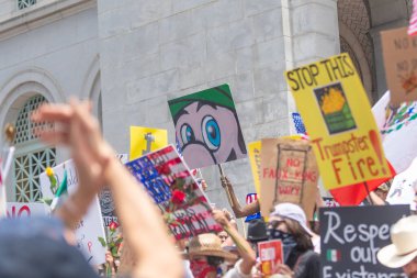 Los Angeles, Kaliforniya, ABD, 14 Temmuz 2025, Hükümetin politikalarını protesto eden ve demokrasi ve göçmen haklarını destekleyen protestocular ellerinde sloganlar tutuyorlar..