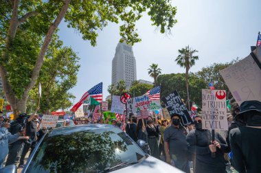 Los Angeles, Kaliforniya, ABD, 14 Temmuz 2025, Hükümetin politikalarını protesto eden ve demokrasi ve göçmen haklarını destekleyen protestocular ellerinde sloganlar tutuyorlar..