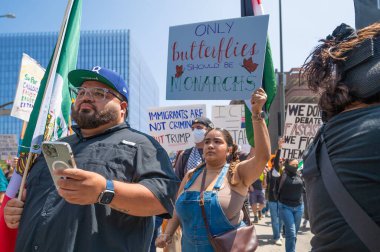 Los Angeles, Kaliforniya, ABD, 14 Temmuz 2025, Hükümetin politikalarını protesto eden ve demokrasi ve göçmen haklarını destekleyen protestocular ellerinde sloganlar tutuyorlar..