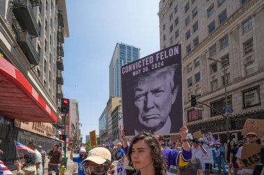 Los Angeles, Kaliforniya, ABD, 14 Temmuz 2025, Hükümetin politikalarını protesto eden ve demokrasi ve göçmen haklarını destekleyen protestocular ellerinde sloganlar tutuyorlar..