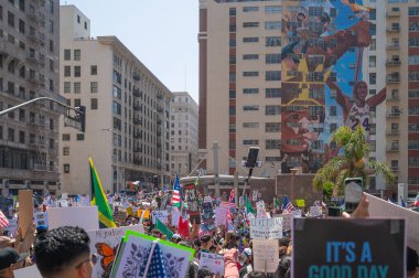 Los Angeles, Kaliforniya, ABD, 14 Temmuz 2025, Hükümetin politikalarını protesto eden ve demokrasi ve göçmen haklarını destekleyen protestocular ellerinde sloganlar tutuyorlar..