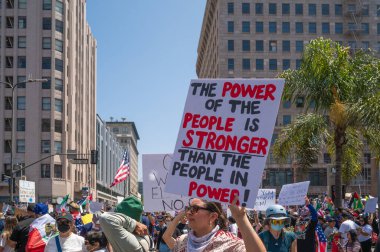 Los Angeles, Kaliforniya, ABD, 14 Temmuz 2025, Hükümetin politikalarını protesto eden ve demokrasi ve göçmen haklarını destekleyen protestocular ellerinde sloganlar tutuyorlar..
