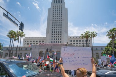 Los Angeles, Kaliforniya, ABD, 14 Temmuz 2025, Hükümetin politikalarını protesto eden ve demokrasi ve göçmen haklarını destekleyen protestocular ellerinde sloganlar tutuyorlar..