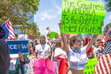 Los Angeles, Kaliforniya, ABD, 14 Temmuz 2025, Hükümetin politikalarını protesto eden ve demokrasi ve göçmen haklarını destekleyen protestocular ellerinde sloganlar tutuyorlar..