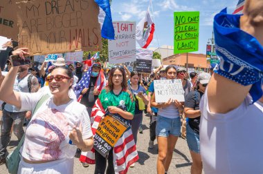 Los Angeles, Kaliforniya, ABD, 14 Temmuz 2025, Hükümetin politikalarını protesto eden ve demokrasi ve göçmen haklarını destekleyen protestocular ellerinde sloganlar tutuyorlar..