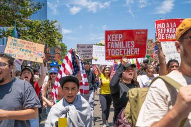 Los Angeles, Kaliforniya, ABD, 14 Temmuz 2025, Hükümetin politikalarını protesto eden ve demokrasi ve göçmen haklarını destekleyen protestocular ellerinde sloganlar tutuyorlar..