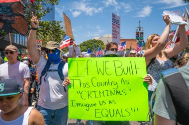 Los Angeles, Kaliforniya, ABD, 14 Temmuz 2025, Hükümetin politikalarını protesto eden ve demokrasi ve göçmen haklarını destekleyen protestocular ellerinde sloganlar tutuyorlar..