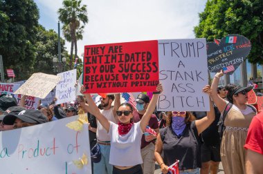 Los Angeles, Kaliforniya, ABD, 14 Temmuz 2025, Hükümetin politikalarını protesto eden ve demokrasi ve göçmen haklarını destekleyen protestocular ellerinde sloganlar tutuyorlar..
