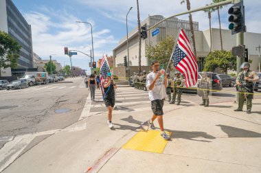 Los Angeles, Kaliforniya, ABD, 14 Temmuz 2025, Hükümet politikalarını protesto eden Krallar Yok sırasında Amerikan bayrakları taşıyan polis memurlarının önünden geçen protestocular