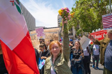 Los Angeles, Kaliforniya, ABD, 14 Temmuz 2025, Hükümetin politikalarını protesto eden ve demokrasi ve göçmen haklarını destekleyen bir buket çiçek tutan protestocu