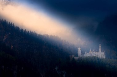 Gündoğumunda ünlü Neuschwanstein şatosu. Arka planda renkli Alpler manzarası var.
