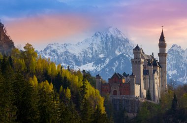 Gündoğumunda ünlü Neuschwanstein şatosu. Arka planda renkli Alpler manzarası var.