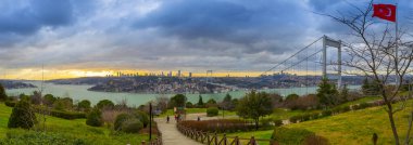 Güneş batarken Otagtepe 'den Boğaz' a panoramik bir manzara. Türk bayrağı ve sağ tarafta FSM Köprüsü..