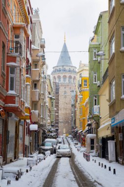 İstanbul 'da kış. Dar bir sokaktan tarihi Galata Kulesi manzarası ve karlı hava.