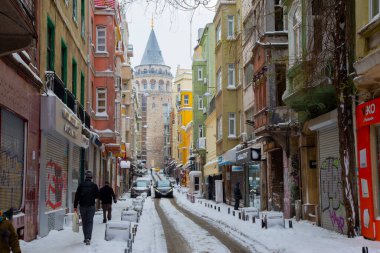 İstanbul 'da kış. Dar bir sokaktan tarihi Galata Kulesi manzarası ve karlı hava.