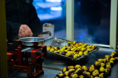 Açık hava kestane kızartma makinesi, kestane ölçme bardakları ve tahta kaşıkla.