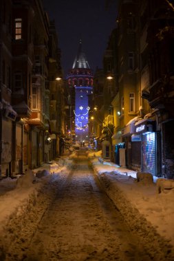 İstanbul 'da kış. Dar bir sokaktan tarihi Galata Kulesi manzarası ve karlı hava.