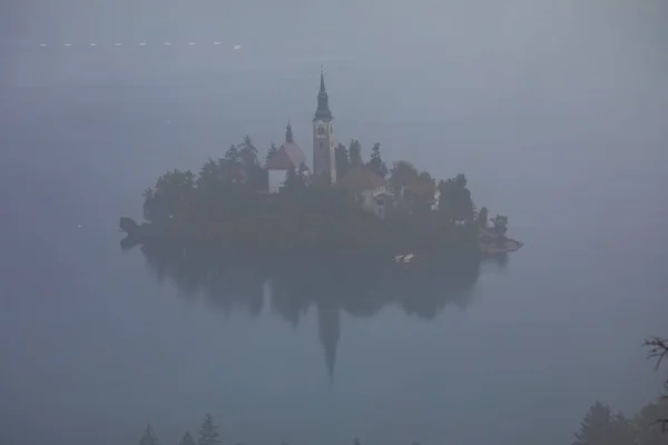 Bled湖の島の空中ビューは 背景にBled市と 島内の教会などの建物は水面に映る — ストック写真