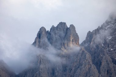 Sonbaharda gün batımında güzel bir evi ve kilisesi olan dağ vadisi. Binalar, yüksek kayalar, renkli gökyüzü, bulutlar, güneş ışığı olan manzara. Dolomites, İtalya 'daki Tre Cime parkındaki dağlar. İtalyan Alpleri