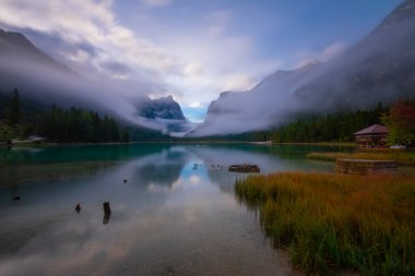 Toblacher Gölü (Lago di Dobbiaco) ve Dolomite dağları üzerinde panoramik manzara sisli bir sabah, Dolomitler, Güney Tyrol, İtalya 'nın geniş açılı renklerinde, sonbahar mevsiminde yakınlarda zirveler yapar.