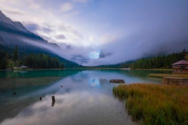 Toblacher Gölü (Lago di Dobbiaco) ve Dolomite dağları üzerinde panoramik manzara sisli bir sabah, Dolomitler, Güney Tyrol, İtalya 'nın geniş açılı renklerinde, sonbahar mevsiminde yakınlarda zirveler yapar.