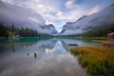 Toblacher Gölü (Lago di Dobbiaco) ve Dolomite dağları üzerinde panoramik manzara sisli bir sabah, Dolomitler, Güney Tyrol, İtalya 'nın geniş açılı renklerinde, sonbahar mevsiminde yakınlarda zirveler yapar.