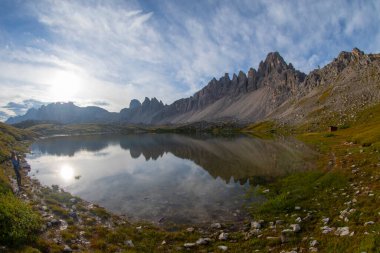 Güneşli bir günde bulutlu bir dağ vadisi. Köprüsü olan bir manzara, yüksek kayalar, renkli mavi gökyüzü, bulutlar, güneş ışığı. Dolomites, İtalya 'daki Tre Cime parkındaki dağlar. İtalyan Alpleri.