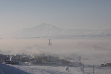Bitlis Hizan , a mosque and village covered in fog and snow .