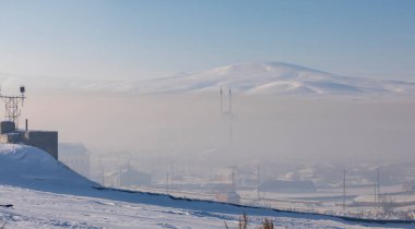 Bitlis Hizan , a mosque and village covered in fog and snow .