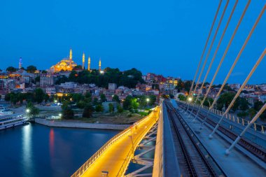 İstanbul 'da metro, Haliç yer istasyonu, Fatih ilçesi ve arkada Süleyman camisi, köprüde yürüyen insanlar, gün batımı