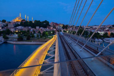 İstanbul 'da metro, Haliç yer istasyonu, Fatih ilçesi ve arkada Süleyman camisi, köprüde yürüyen insanlar, gün batımı