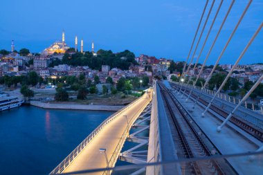 İstanbul 'da metro, Haliç yer istasyonu, Fatih ilçesi ve arkada Süleyman camisi, köprüde yürüyen insanlar, gün batımı