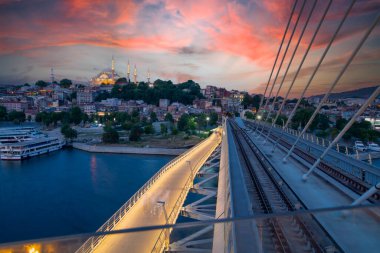 İstanbul 'da metro, Haliç yer istasyonu, Fatih ilçesi ve arkada Süleyman camisi, köprüde yürüyen insanlar, gün batımı